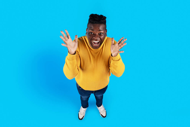 Top View Of Excited Black Guy Spreading Hands With Surprise, Emotional African American Man Looking At Camera And Screaming Wow, Standing Isolated Over Blue Studio Background, Copy Space - Photo, Image