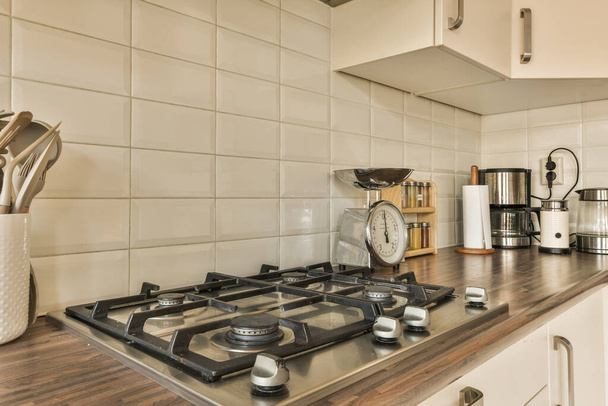 a kitchen with white tiles on the walls and wood counters in front of the stovetop, which is being used for cooking - Foto, Imagen