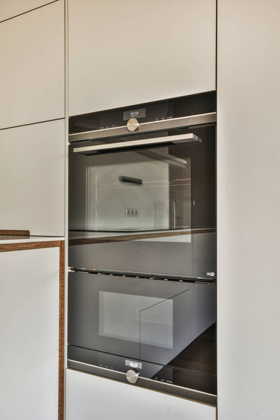 o interior de um forno em uma cozinha com armários brancos e guarnições de madeira na porta, que está aberta - Foto, Imagem