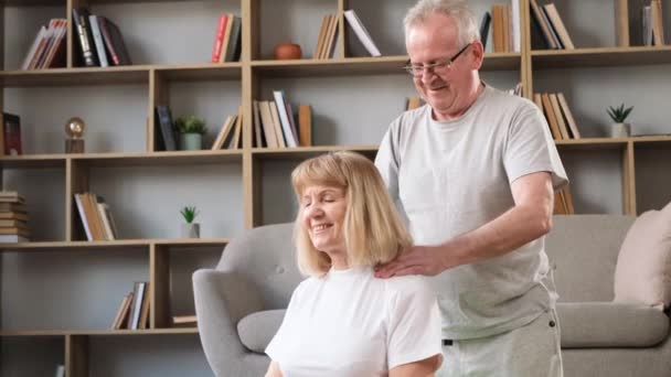 Um avô grisalho dá uma massagem no pescoço à avó. feliz casal sénior relaxante em casa. - Filmagem, Vídeo