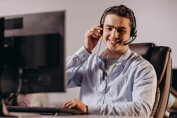 Smiling call center operator enjoying his work. Cheerful customer support agent in headphones consulting client. High quality photo - Photo, Image