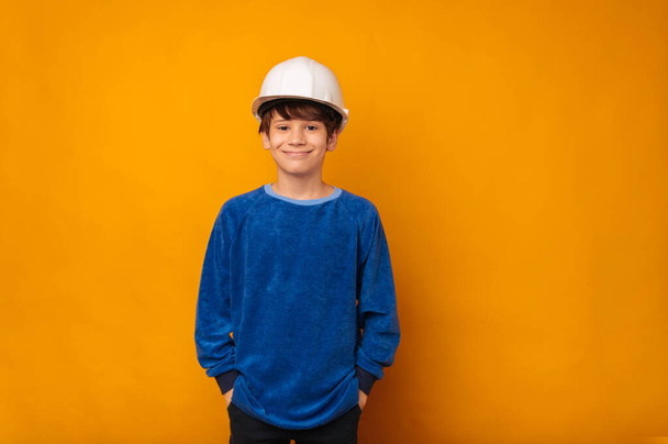 笑顔ティーン男の子身に着けています白い保護ハード帽子エンジニアであることについて考えています. - 写真・画像