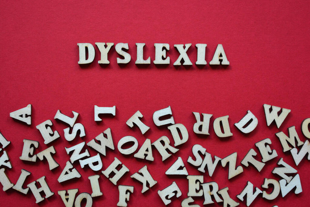 Dysleksja, słowo w drewnianych liter alfabetu otoczony losowymi literami na czerwonym tle - Zdjęcie, obraz
