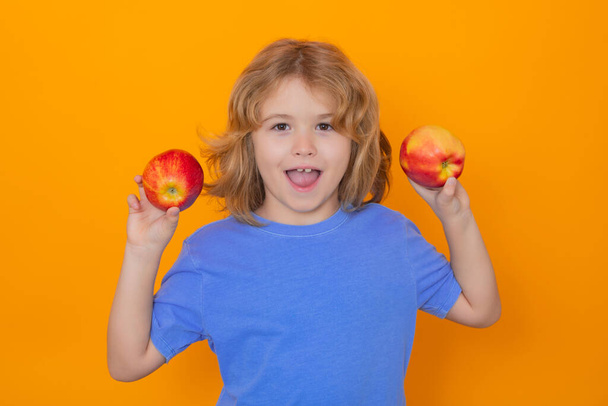Παιδί με μήλο στο στούντιο. Studio πορτρέτο του χαριτωμένο παιδί κρατήσει το μήλο απομονώνονται σε κίτρινο φόντο - Φωτογραφία, εικόνα