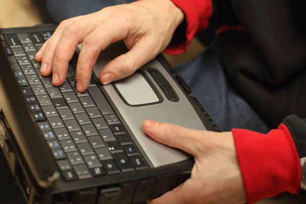 a person holding an old laptop on his lap - Photo, Image