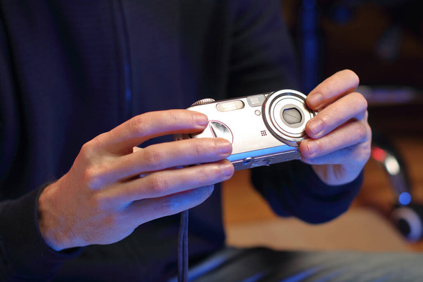 een persoon houdt een oude compacte camera in zijn handen voor zich - Foto, afbeelding
