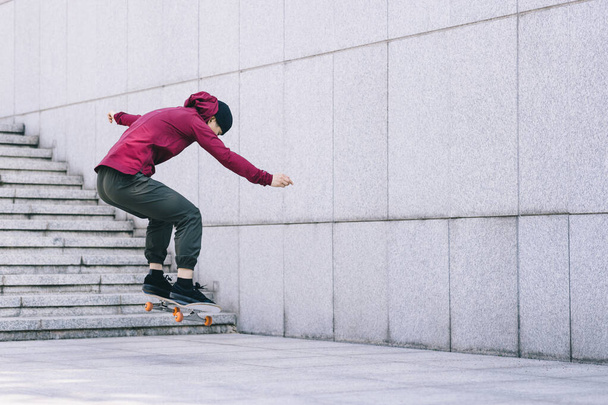 Asian woman skateboarder skateboarding in modern city - Fotó, kép