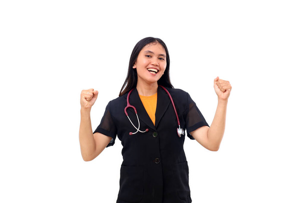 Excited Young asian doctor standing while draping a stethoscope with clenched hands. Isolated - Photo, Image