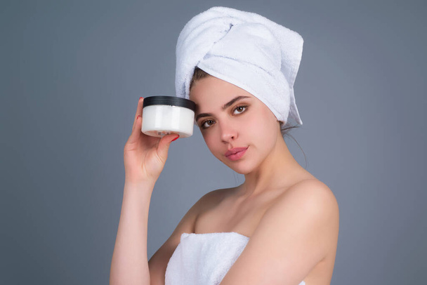 Beauty portrait of a beautiful half naked woman applying face cream isolated on studio background. Skin care product. Moisturizing creme on face. Perfect skin, morning routine - Foto, afbeelding