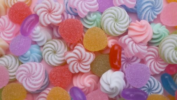 Színes cukorkák, édességek és nyalókák keveréke forog. Édes cukros desszert. Ünnepi háttér nyaraláshoz vagy gyermekszületésnaphoz. - Felvétel, videó