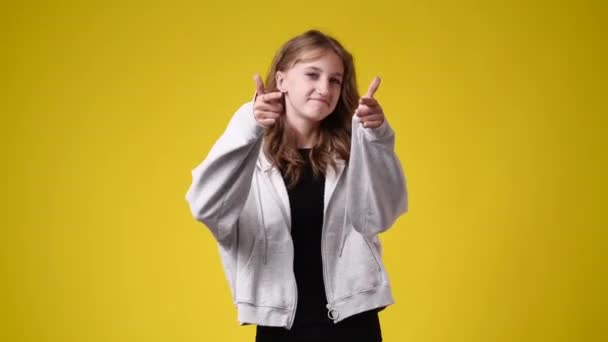 4k video of one girl showing thumbs up and smiling over yellow background. Concept of emotions. - Video