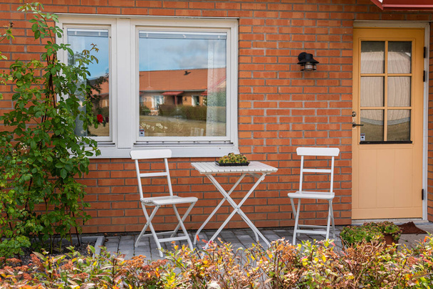 İsveç, Knislinge 4 Eylül 2022: Terasta, verandada dinlenmek için sandalyeler ve masa. Rahatlatıcı bölge. Eğlence alanı olarak. Sıcak ve rahat bir atmosfer. Güneşli bir gün. Özel ev.  - Fotoğraf, Görsel