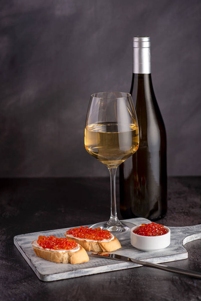 Food photography of sandwich with caviar, pink salmon, white wine, bottle, starter, delicacy - Foto, afbeelding