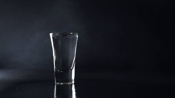 Glass of Vodka on a black background. Drink Transparent Glass on a black background. Isolate. Copy space - Photo, Image