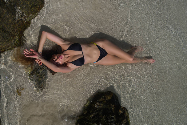 Sexy girl laying on sand beach. Beautiful sexy woman in bikini lingerie swimwear on sea. Sexy girl with perfect body. Hot tanned female model on beach. Summer beach - Foto, Bild