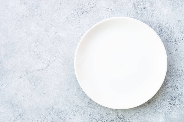 White plate at light stone table. Empty plate. Flat lay image. - Zdjęcie, obraz