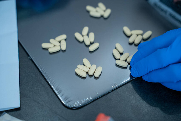 Comprimidos para tratamento são ordenadamente dispostos em uma mesa escura no laboratório - Foto, Imagem