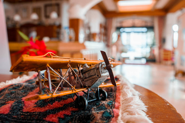 Closeup of wooden figurine of propeller airplane with textile decorated on table at alpine hotel room - Foto, Imagen