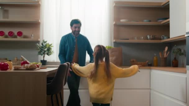 Zamyślony mężczyzna stojący w kuchni mała córeczka dzieciak biegnie do taty biegnąc do ojca tatuś podnieść dziecko przędzenia śliczne dziecko spin girl wokół wirujące przytulanie. Kaukaska więź rodzinna w domu - Materiał filmowy, wideo