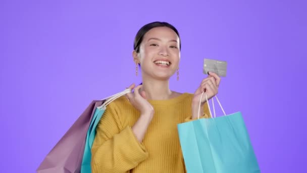 Τσάντα αγορών, πιστωτική κάρτα και λιανική πώληση με Ασιάτισσα στο στούντιο για προσφορά, έκπτωση και πωλήσεις. Χρηματοδότηση, προώθηση και πληρωμή με πελάτη κορίτσι για τον πλούτο, το προϊόν και την προσφορά σε μωβ φόντο. - Πλάνα, βίντεο