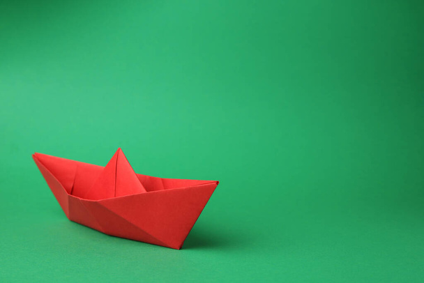 Origami art. Paper boat on green background, space for text - Фото, изображение