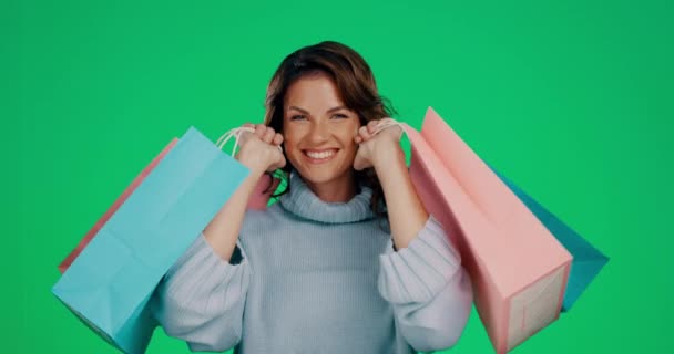 Frau, Einkaufstaschen und Lächeln für Mode, Rabatt oder Verkauf vor grünem Studiohintergrund. Porträt einer glücklichen Shopperin, die in freudigem Glück für stilvolle Kleidungsgeschenke auf Attrappe lächelt. - Filmmaterial, Video