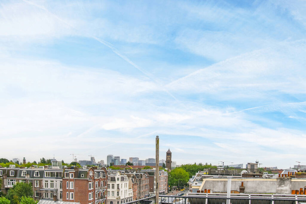 Amsterdam, Holandia - 10 kwietnia 2021 r.: obszar miejski z budynkami i drzewami na czele, zaczerpnięty z wysokiego kąta w dzień przejrzystego nieba - Zdjęcie, obraz