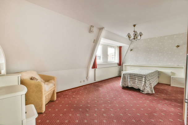 una camera da letto con un letto, sedia e specchio sulla parete di fronte alla stanza è presa dall'alto - Foto, immagini