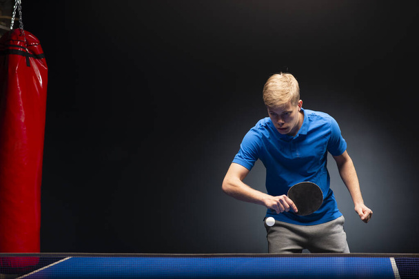 Retrato de un joven jugando al tenis sobre fondo negro - Foto, Imagen