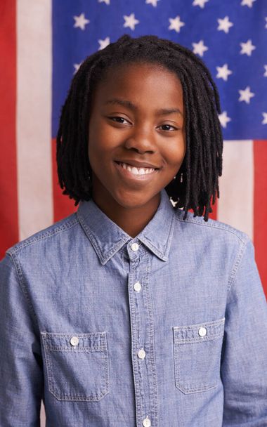 Stolz auf seine Nation. Porträt eines glücklichen Jungen, der vor einer amerikanischen Flagge steht - Foto, Bild
