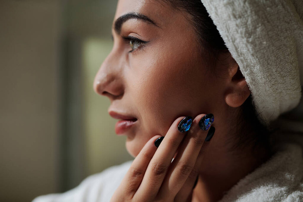 Closeup image of woman applying face cream after taking bath - 写真・画像