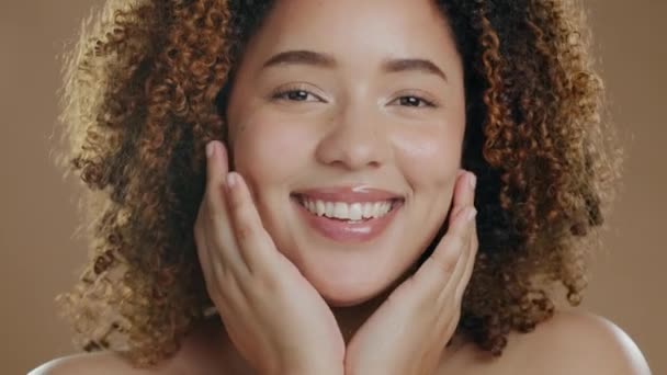 Face, black woman and cosmetics for dermatology, beauty and lady against a brown studio background. Portrait, Jamaican female and lady with skincare, wellness and salon treatment or grooming for glow. - Footage, Video