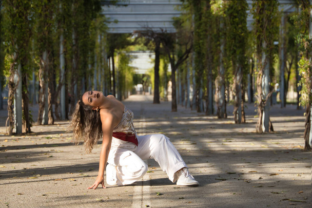Latin and Hispanic girl, young and beautiful, dancing modern dance in the street outdoors. Dance concept, moonwalk, jumpstyle, shuffle, electrodance, hip hop, funky, popping. - Photo, Image