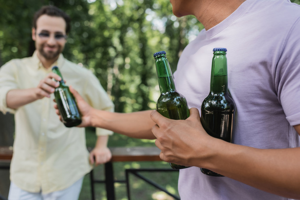 アフリカ系アメリカ人の男性が公園で友達にビールを提供し - 写真・画像