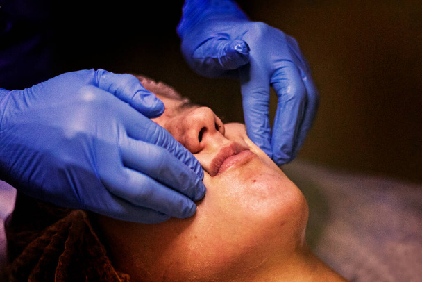haciendo masaje facial con aceites esenciales a una joven - Foto, imagen