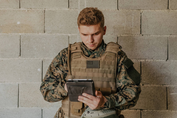 soldato utilizzando computer tablet contro vecchio muro di mattoni. - Foto, immagini