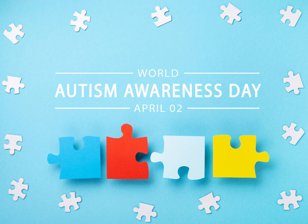 World Autism Awareness Day or month concept (em inglês). Design criativo para 2 de abril. Quebra-cabeças brancos e coloridos, símbolo de consciência para transtorno do espectro do autismo no fundo azul. Vista superior, espaço de cópia. - Foto, Imagem