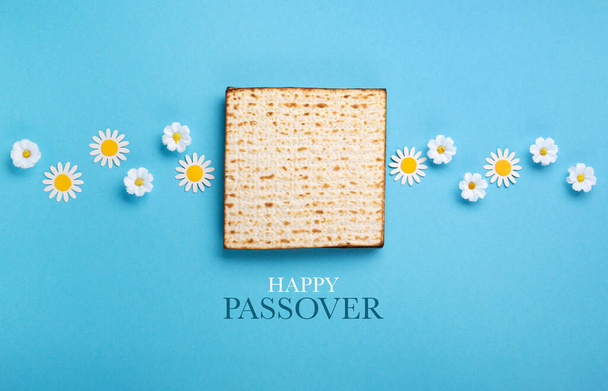 ユダヤ人の休日マツァ、ナッツ、青いテーブルの春の花と過越の挨拶カードの概念。Seder Pesach春休みの背景、トップビュー、コピースペース. - 写真・画像