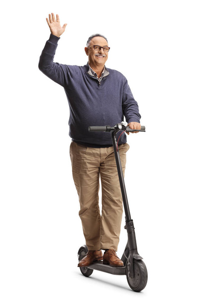 Cheerful mature man riding an electirc scooter and waving isolated on white background - Valokuva, kuva