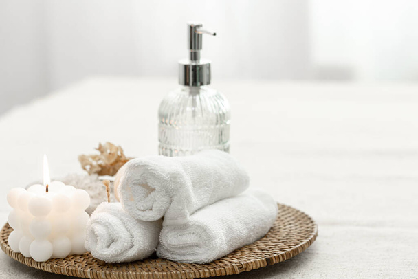 Spa composition with towels, candle and soap dispenser on blurred white background, copy space. - Photo, image