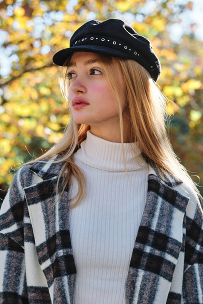 Vertical portrait of a beauty blonde woman with hat posing distracted looking away outdoors - 写真・画像