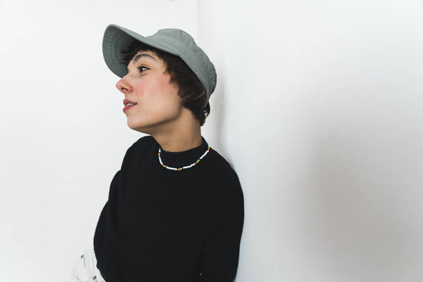 Mittlere Seitenaufnahme einer Frau mit gescheitelten Lippen, die eine Mütze, eine Halskette und einen schwarzen Pullover trägt. Hochwertiges Foto - Foto, Bild