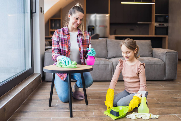 Happy mother and daughter cleaning house together. - Valokuva, kuva