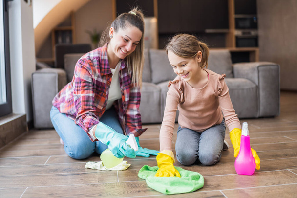 Happy mother and daughter cleaning house together. - Photo, image