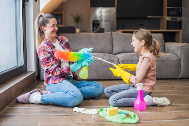 Happy mother and daughter having fun while cleaning  house together. - Photo, Image