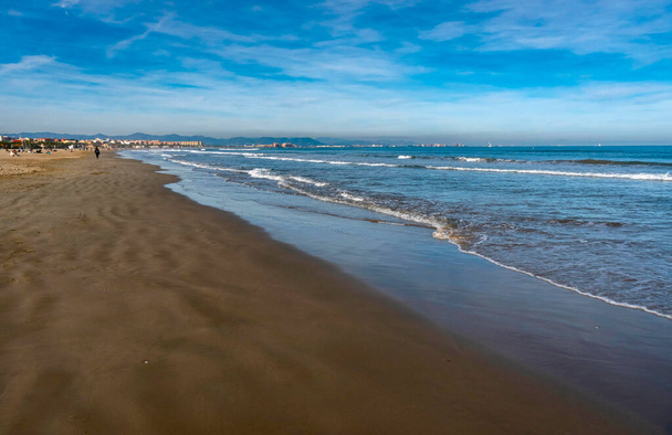 Dezembro 2022 - Valência, Espanha - Mar mediterrâneo de inverno com multidões de pessoas caminhando e surfistas - Foto, Imagem