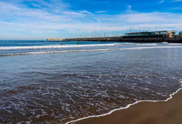 Grudzień 2022 - Walencja, Hiszpania - Zimowe Morze Śródziemne z tłumami spacerujących ludzi i surferów - Zdjęcie, obraz