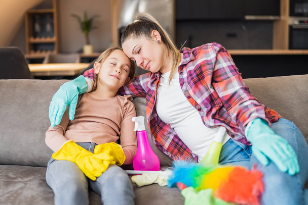 Happy mother and daughter resting after cleaning their house together. - Foto, Imagen