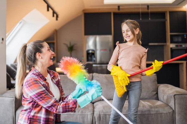 Happy mother and daughter having fun while cleaning  house together. - Foto, immagini