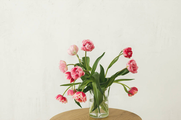 Stylowy piękny różowy bukiet tulipanów w wazonie na drewnianym stole w rustykalnym pokoju. Kwiatowa kompozycja na farmie. Kompozycja wiosennych kwiatów, przestrzeń do kopiowania. Szczęśliwego dnia matek i kobiet - Zdjęcie, obraz